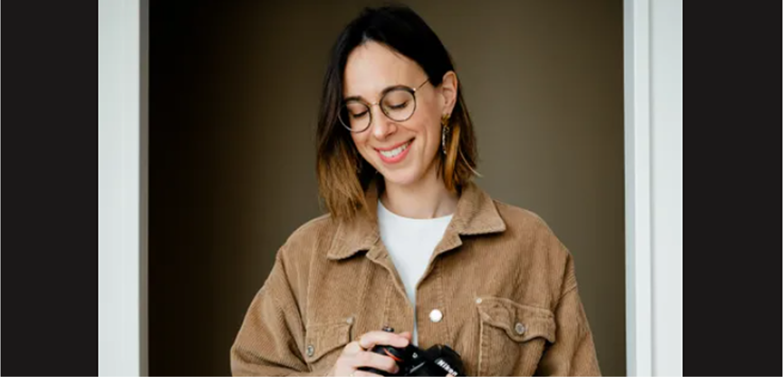 Une jeune femme souriante avec un appareil photo dans les mains